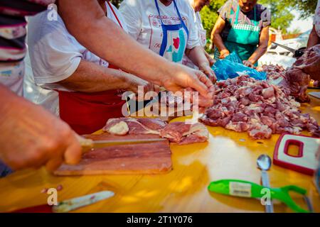 Blick auf Senioren, ältere Menschen, Rentner, Männer und Frauen stehen und schneiden frisches rohes Fleisch auf Holzbrettern mit Messern A in kleinere Stücke Stockfoto