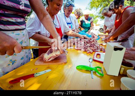 Blick auf Senioren, ältere Menschen, Rentner, Männer und Frauen stehen und schneiden frisches rohes Fleisch auf Holzbrettern mit Messern A in kleinere Stücke Stockfoto