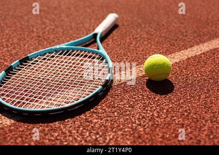 Bälle und Schläger liegen auf einem lehmbraunen professionellen Tennisplatz in der Nähe von Tennisbällen und Schläger auf Schlacke auf dem Tennisplatz auf dem Spielplatz Stockfoto