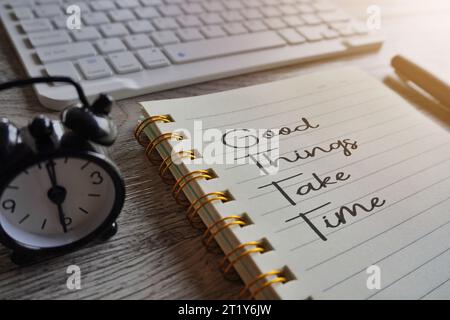 Nahaufnahme eines Notizbuchs mit Text GUTE DINGE BRAUCHEN ZEIT, Uhr und Stift auf dem Tisch. Motivationskonzept Stockfoto