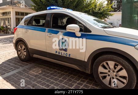 Mohos, Bezirk Lasithi, Kreta, Griechenland. 30.09.2023. Griechischer Polizeiwagen auf blauer Ampel durch eine kleine Stadt auf schmaler Straße. Stockfoto