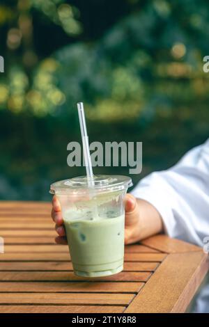 Gefrorener Matcha Latte in einem Plastikbecher in den Händen einer Frau. Stockfoto