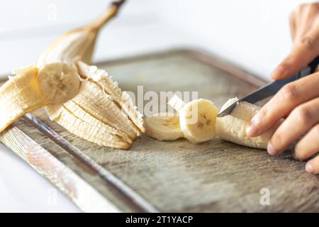 Eine Frau schneidet eine Banane auf einem Schneidebrett. Stockfoto