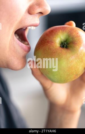 Detaillierte Aufnahme einer Frau, die einen ganzen frischen Apfel isst. Stockfoto