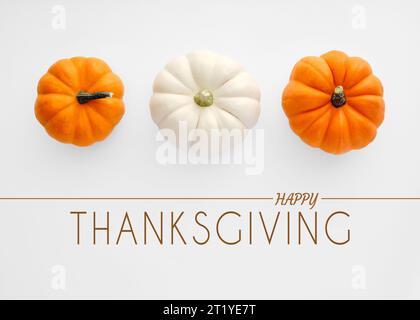 Happy Thanksgiving Text mit weißen und orangen Herbstkürbissen auf weißem Hintergrund. Draufsicht. Stockfoto