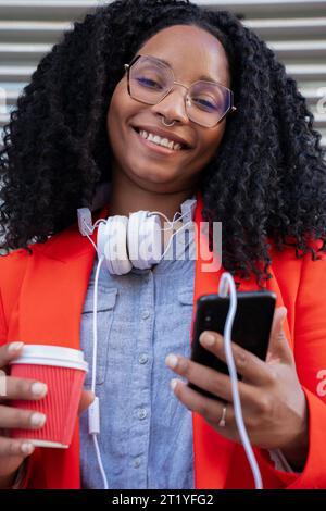 Porträt einer jungen, lächelnden schwarzen Geschäftsfrau mit Handy und Kaffee Stockfoto
