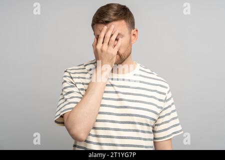 Enttäuschter gestresster Mann mittleren Alters, der eine Facepalm-Geste macht und sich selbst für einen Fehler verantwortlich macht Stockfoto