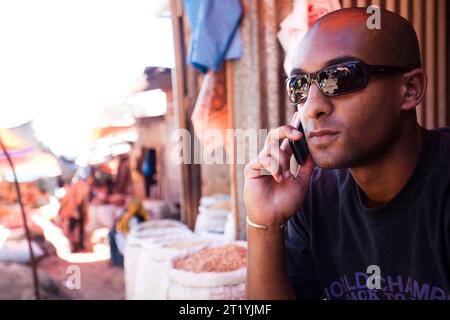 Ein junger Mann aus Äthiopien arbeitet auf seinem Handy, während er einen Gewürzmarkt in Harar, Äthiopien, besucht. Stockfoto