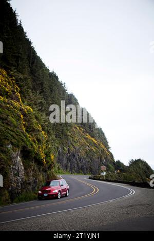 Ein rotes Auto fährt durch eine kleine Straße an der Küste der USA. Stockfoto