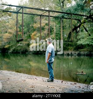 Ein Porträt eines Mannes neben einem stillen Fluss und einem grünen Wald. Stockfoto
