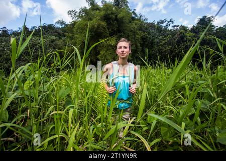 Eine junge Frau wandert durch den Dschungel von Puerto Rico auf einem Abenteuer an einem sonnigen Tag. Stockfoto