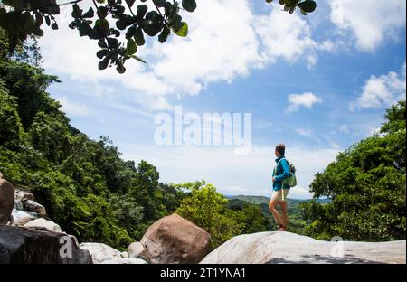 Eine Frau steht auf einem Felsvorsprung mit Blick auf den Dschungel von Puerto Rico. Stockfoto