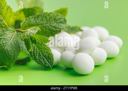 Minzbonbons. Menthol-Bonbons und Minzblätter auf grünem Hintergrund. Stockfoto