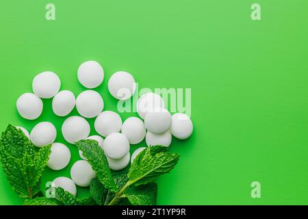 Minzbonbons. Menthol-Bonbons und Minzblätter auf grünem Hintergrund. Draufsicht. Stockfoto