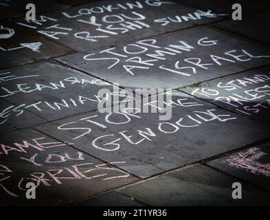 Die gemalten Demonstranten stoppen den Völkermord mit Kreide auf der Straße während des Pro-Palästina-Protestes in London . Stockfoto