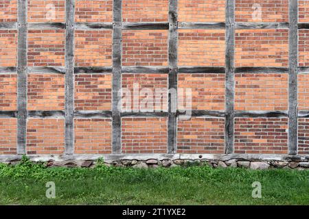 Alte Ziegelmauer und grünes Gras. Hintergrund und Textur für Design. Stockfoto