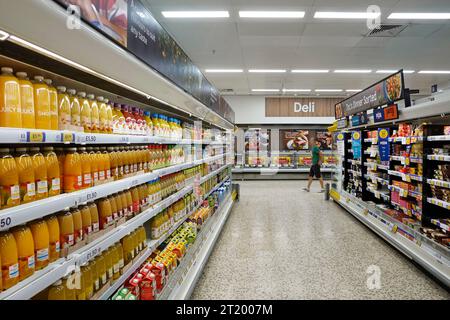 Einkaufsmöglichkeiten im Tesco Extra Supermarkt gehen vorbei an einem Deli-Thekenschild in Richtung Regalgang mit Lebensmittel- und Getränkehändler England Großbritannien Stockfoto