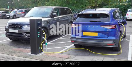 Schließen Sie ein blaues elektrisches Honda Auto und Stromkabel an die Ladestation für Autofahrer, die den Holiday Inn Parkplatz Essex England, Großbritannien besuchen Stockfoto