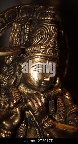 Nahaufnahme einer glänzenden Steinskulptur des hinduistischen Gottes krishna, der seine Flöte in einem alten Tempel spielt Stockfoto