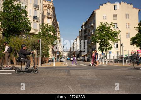 Mann sitzt auf einem Roller, der auf der französischen Straße vorbeifährt Stockfoto