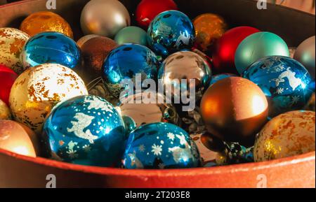Eine Schüssel gefüllt mit bunten weihnachtskugeln und Ornamenten. Die Schale besteht aus braunem Material und die Kugeln sind in verschiedenen Farben Stockfoto