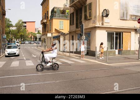 Mann, der auf einem kleinen Fahrrad über die Straße fährt, mit Straßenszene Stockfoto