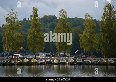 Gruppe von kleinen Booten am Strand mit Baggern und Industriemaschinen im Hintergrund. Lahti, Finnland. September 2023. Stockfoto