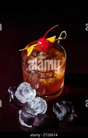 Durstlöschende negroni mit Cocktailkirsche und Eiswürfeln vor schwarzem Hintergrund, Konzept Stockfoto