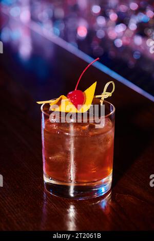 Ästhetischer eleganter negroni-Cocktail dekoriert mit Kirschbaum und Bar im Hintergrund, Konzept Stockfoto
