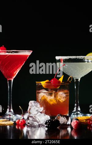 Durstlöschende Cocktails garniert mit Kirschen und Limette auf schwarzem Hintergrund, Konzept Stockfoto