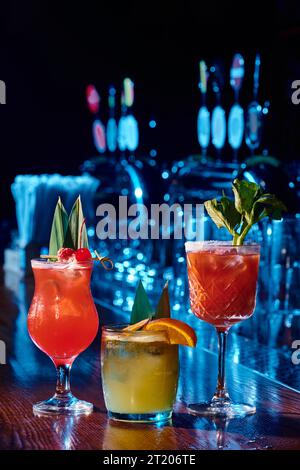 Drei verschiedene erfrischende Cocktails auf der Bartheke mit Bar im Hintergrund, Konzept Stockfoto