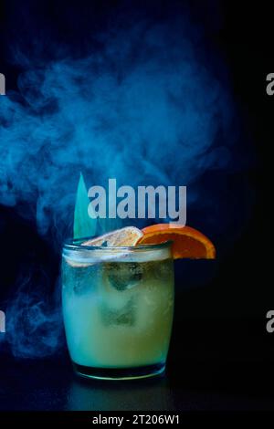 Raffinierter altmodischer Cocktail mit Garnitur auf schwarzem rauchigen Hintergrund, Konzept Stockfoto