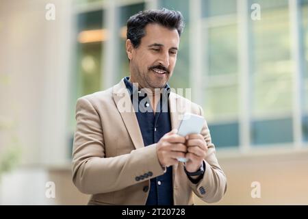 Gutaussehender reifer Mann im formellen Anzug Manager mit Smartphone im Freien Stockfoto