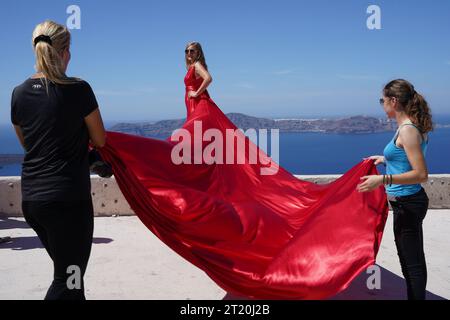 Zwei Assistenten halten den Zug des Models in einem roten Kleid. Stockfoto