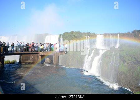 Touristen an den Iguazu Falls, einem der großen Naturwunder der Welt, an der Grenze zwischen Brasilien und Argentinien. regenbogen im Vordergrund Stockfoto