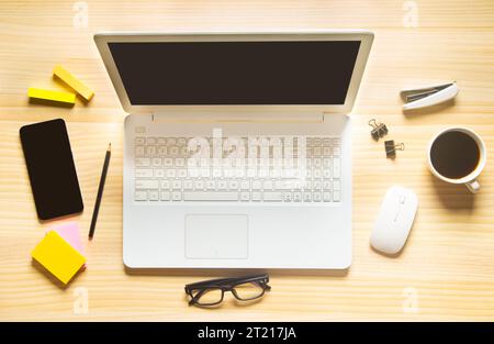 Holzschreibtischbüro mit Laptop, Smartphone und anderen Arbeitsmaterialien mit einer Tasse Kaffee. Draufsicht mit Kopierraum für die Texteingabe. Arbeitsbereich des Konstrukteurs o Stockfoto