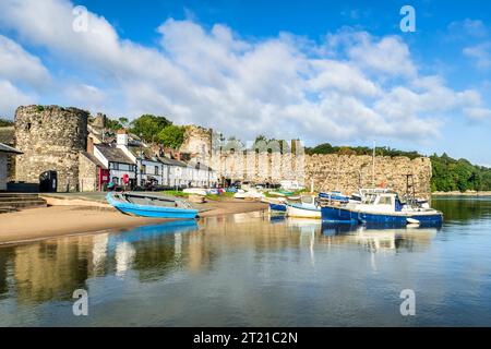 29. September 2023: Conwy, Nordwales - Boote, die entlang der Flussmündung des River Conwy befestigt sind, und Landhäuser, die an den Stadtmauern des 13. Jahrhunderts gebaut wurden, auf einem... Stockfoto