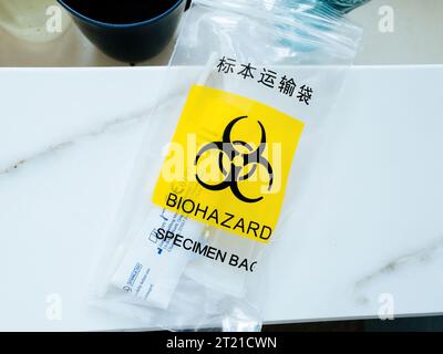 Gelbes Schild auf einem Plastikbeutel mit Probentext in Englisch und Chinesisch - wird zu Hause COVID-19-Test unterzogen Stockfoto