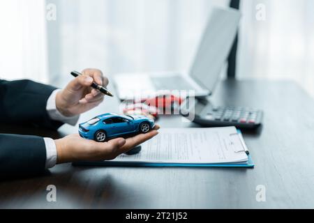 Geschäftskonzept, Kfz-Versicherung, Auto verkaufen und kaufen, Kfz-Finanzierung, Kfz-Schlüssel für Kfz-Kaufvertrag. Ein Autohändler erklärt den Kunden über l Stockfoto