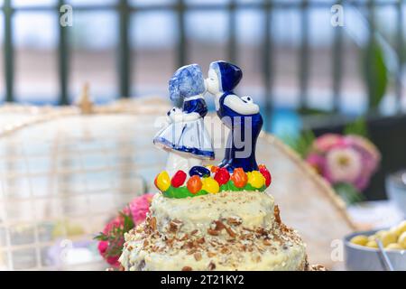 Hochzeitstorte und Partydekoration im Freien, holländische Figur Junge und Mädchen küssen blau. Stockfoto