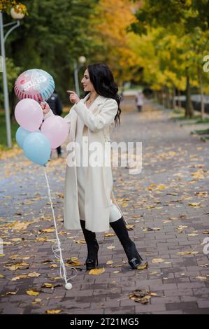 Schöne schwangere Frau mit blauen und rosa aufblasbaren Ballons. Aufblasbare Ballons, mit denen Sie das Geschlecht Ihres ungeborenen Kindes herausfinden können. Ge Stockfoto