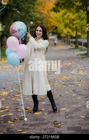 Schöne schwangere Frau mit blauen und rosa aufblasbaren Ballons. Aufblasbare Ballons, mit denen Sie das Geschlecht Ihres ungeborenen Kindes herausfinden können. Ge Stockfoto