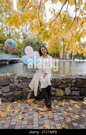 Schöne schwangere Frau mit blauen und rosa aufblasbaren Ballons. Aufblasbare Ballons, mit denen Sie das Geschlecht Ihres ungeborenen Kindes herausfinden können. Ge Stockfoto