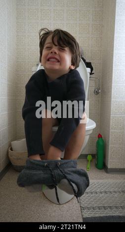 Ein kleiner Junge sitzt auf Toilette im Badezimmer, Kindertopf-Training-Konzept im vertikalen Video Stockfoto