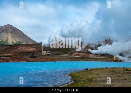 Landschaft des Gebiets Myvatn im Norden Islands, mit einem geothermischen Kraftwerk und einem blauen Schwefelsee, Berge im Hintergrund Stockfoto