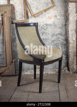 Vintage-Stil. Defekter alter, kaputter Stuhl in einem alten, schmutzigen Zimmer mit anderen alten Sachen Stockfoto
