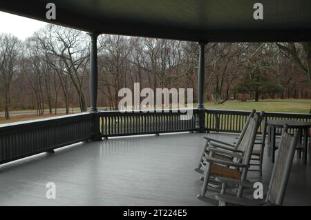 Schaukelstühle säumen die hölzerne Veranda von Sagamore Hill, dem historischen Wohnhaus von Präsident Theodore Roosevelt in New York, das amerikanische Wohndesign des frühen 20. Jahrhunderts repräsentiert. Stockfoto