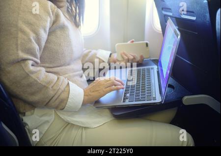 Eine nicht erkennbare Frau benutzt einen Laptop im Flugzeugsitz Stockfoto