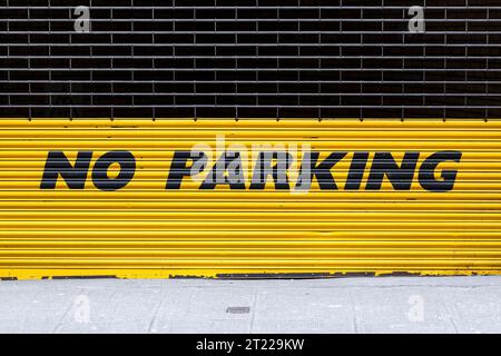 Ein gelbes Schild „kein Parken“ an einer industriellen Rollladentür Stockfoto