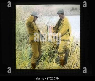 Bohlman zeigt Finley diese Regenbogenforelle während seiner Fotoreise 1905 nach Klamath Marsh. Finleys und Bohlmans Fotografie von der Gegend im Jahr 1905 half Klamath später, 1908 ein Vogelschutzgebiet zu werden. Themen: Vögel; Geschichte; Fische; Freizeit; Wildschutzgebiete. Lage: Oregon. Fish and Wildlife Service Site: KLAMATH MARSH NATIONAL WILDLIFE REFUGE. Sammlung: Wildschutzgebiete. Stockfoto